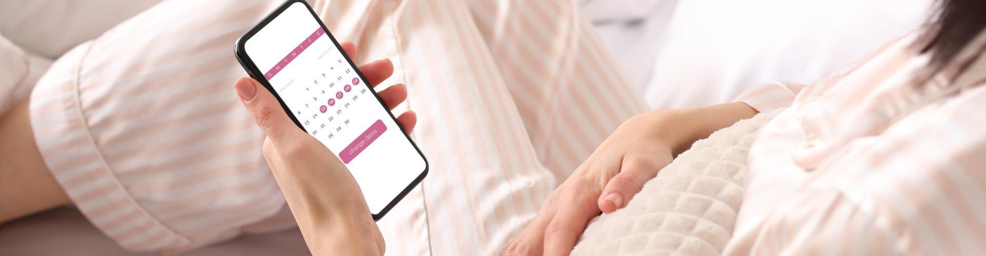 femme consultant une application de suivi du cycle menstruel avec douleurs abdominales