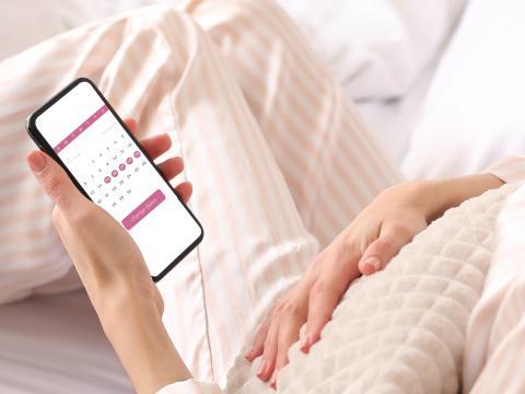femme consultant une application de suivi du cycle menstruel avec douleurs abdominales