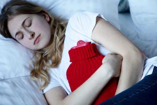 femme utilisant une bouillotte pour soulager les règles douloureuses